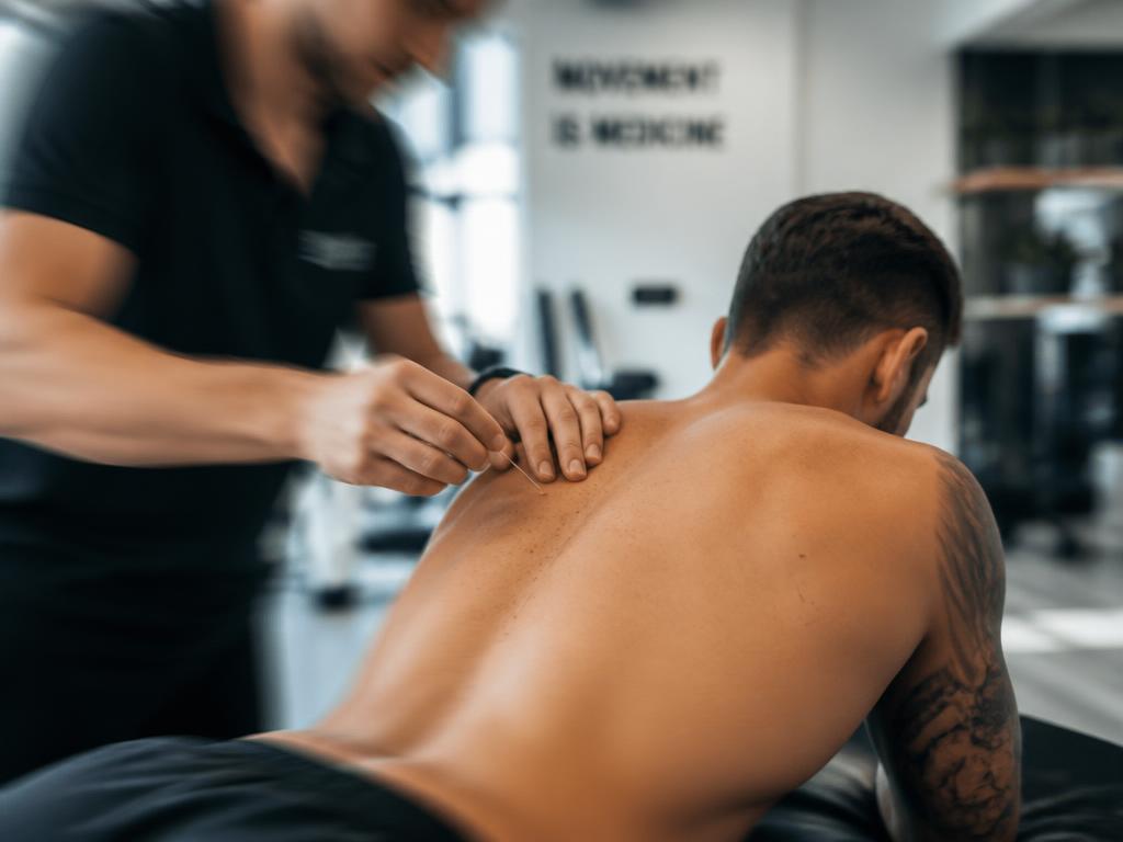 Kinesitherapeut voert dry needling uit op een sporter